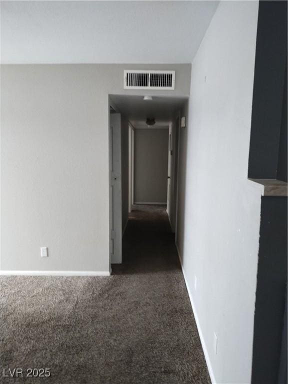 hall with visible vents, baseboards, and carpet floors