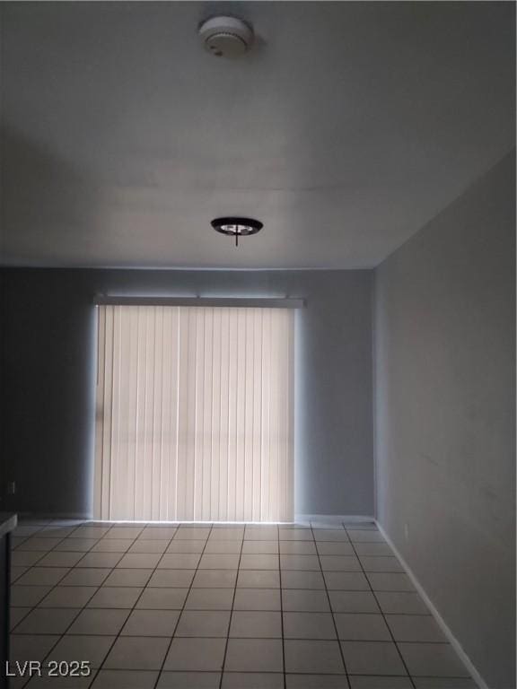 empty room featuring light tile patterned floors and baseboards