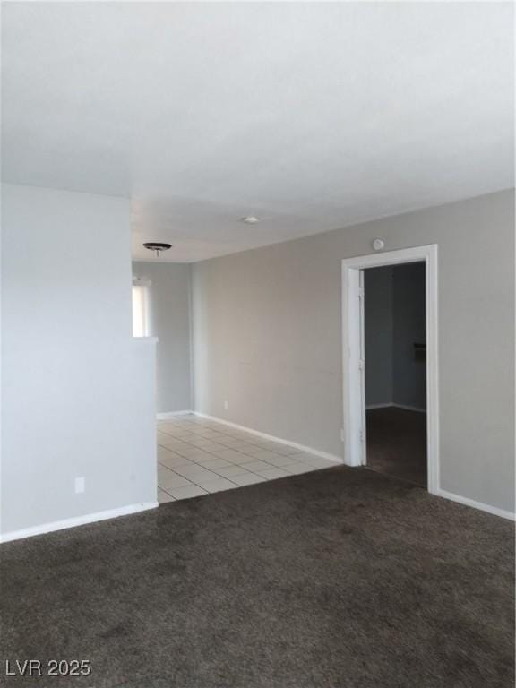 empty room with baseboards, light carpet, and light tile patterned floors
