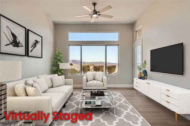 living area with baseboards, ceiling fan, and wood finished floors