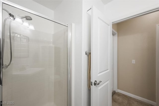 bathroom with baseboards, a shower stall, and tile patterned flooring