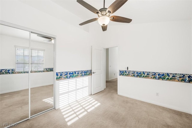 unfurnished bedroom featuring carpet floors, baseboards, ceiling fan, and a closet