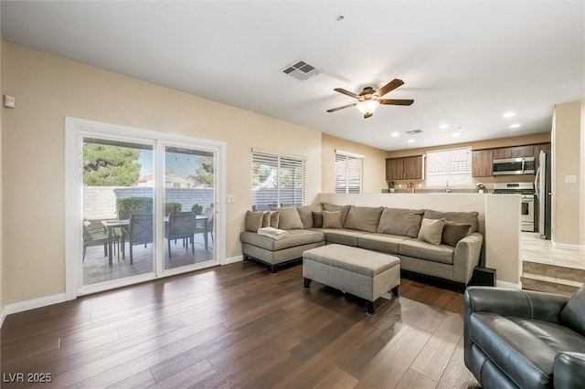 living area featuring a ceiling fan, visible vents, a wealth of natural light, and hardwood / wood-style flooring