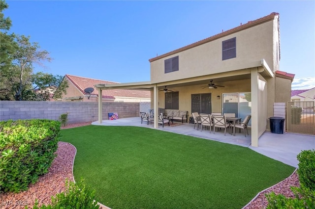 rear view of property featuring ceiling fan, fence, stucco siding, a patio area, and a yard