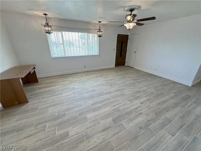 unfurnished living room with a ceiling fan and baseboards