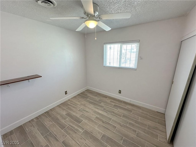 spare room featuring ceiling fan, a textured ceiling, baseboards, wood finished floors, and visible vents