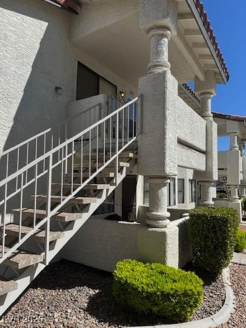 view of side of property with stairs, stucco siding, and a tile roof