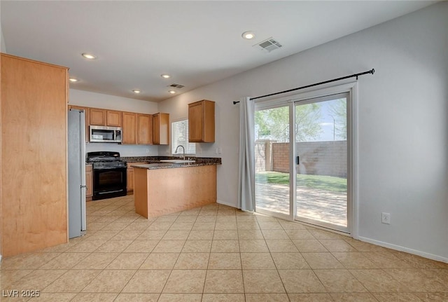 kitchen with dark countertops, appliances with stainless steel finishes, a sink, a peninsula, and visible vents