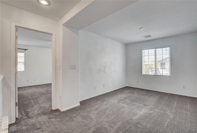empty room with carpet flooring, baseboards, visible vents, and a wealth of natural light