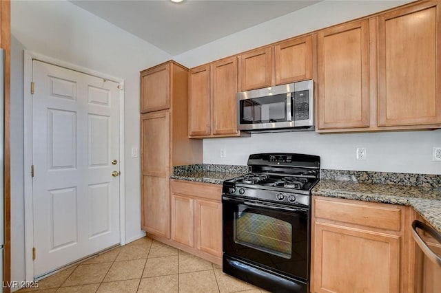 kitchen with light tile patterned floors, dark stone counters, and stainless steel appliances