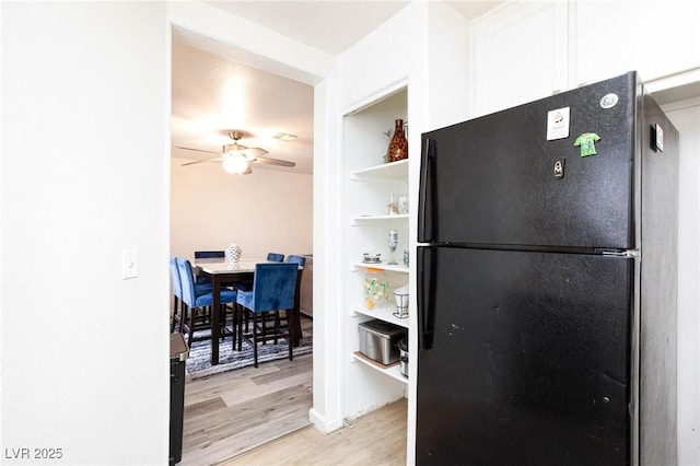 kitchen featuring freestanding refrigerator, white cabinets, light wood-type flooring, and a ceiling fan