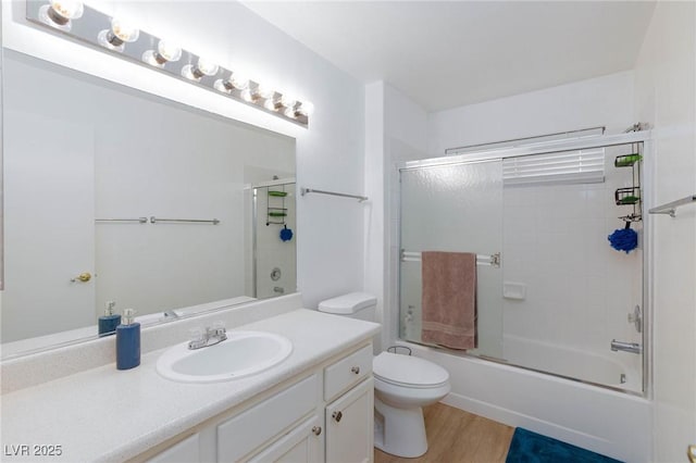 full bathroom with toilet, wood finished floors, vanity, and shower / bath combination with glass door