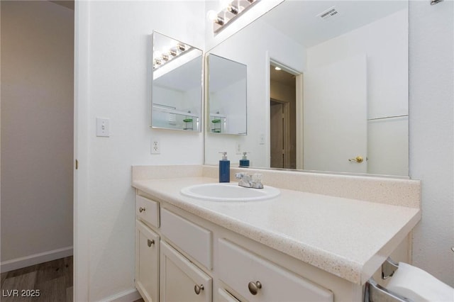 bathroom with baseboards, vanity, visible vents, and wood finished floors