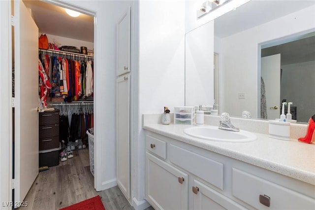 bathroom featuring a walk in closet, wood finished floors, and vanity