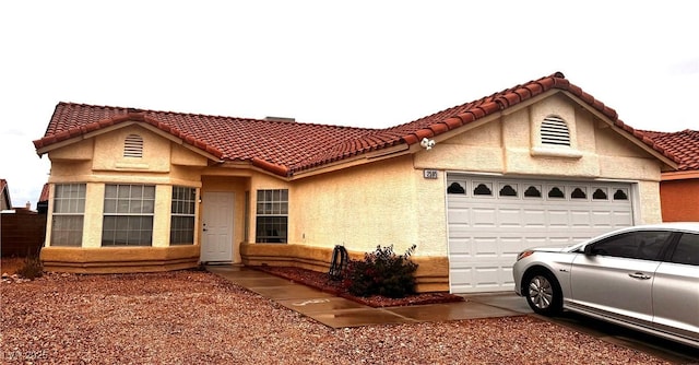 mediterranean / spanish-style house featuring a tiled roof, stucco siding, concrete driveway, and a garage