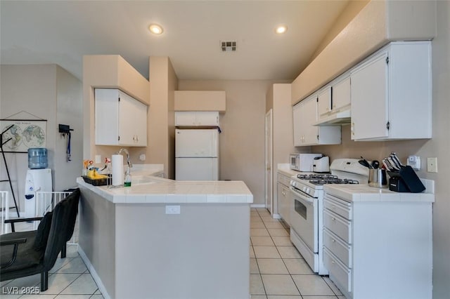 2595 Fort Lauderdale Dr, Las Vegas, NV 89156 - kitchen with white appliances, tile counters, a peninsula, under cabinet range hood, and light tile patterned flooring