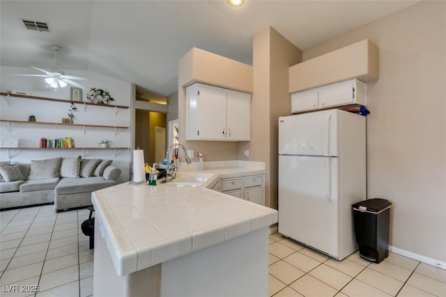 2595 Fort Lauderdale Dr, Las Vegas, NV 89156 - kitchen with freestanding refrigerator, tile counters, a sink, a peninsula, and a ceiling fan