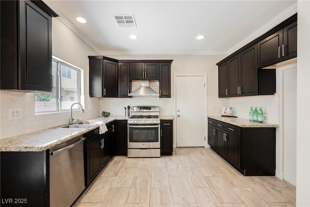kitchen featuring appliances with stainless steel finishes, a sink, wall chimney exhaust hood, backsplash, and visible vents