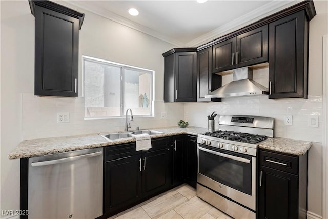 kitchen featuring wall chimney exhaust hood, tasteful backsplash, dark cabinetry, a sink, and stainless steel appliances