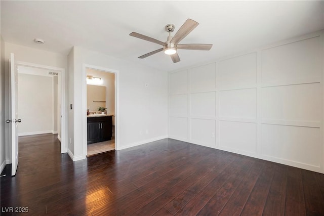 unfurnished room with dark wood-type flooring, baseboards, ceiling fan, and a decorative wall