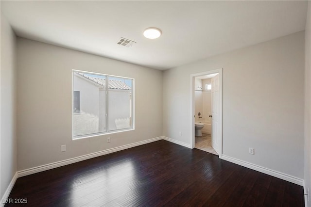 spare room featuring baseboards, visible vents, and dark wood-type flooring