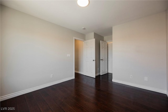 unfurnished bedroom with baseboards and dark wood-type flooring
