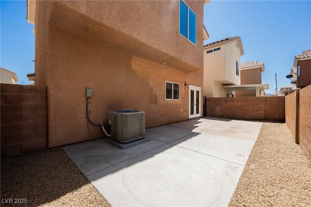back of house featuring stucco siding, a fenced backyard, central AC, and french doors