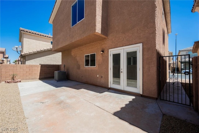 rear view of property with fence, cooling unit, stucco siding, french doors, and a patio area