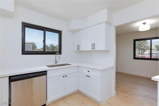 kitchen featuring stainless steel dishwasher, plenty of natural light, a sink, and light countertops