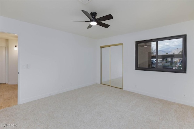 unfurnished bedroom with a closet, carpet flooring, baseboards, and ceiling fan