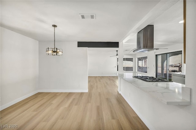 interior space featuring baseboards, visible vents, ceiling fan with notable chandelier, and light wood-type flooring