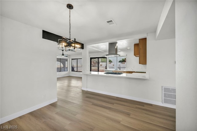 kitchen with brown cabinets, visible vents, island range hood, and an inviting chandelier