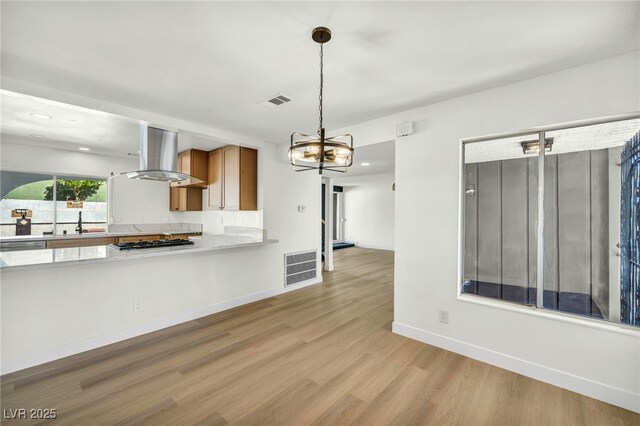 kitchen with ventilation hood, light wood finished floors, a chandelier, and visible vents