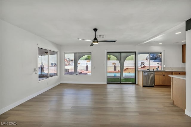 unfurnished living room with a sink, baseboards, recessed lighting, light wood-type flooring, and a ceiling fan