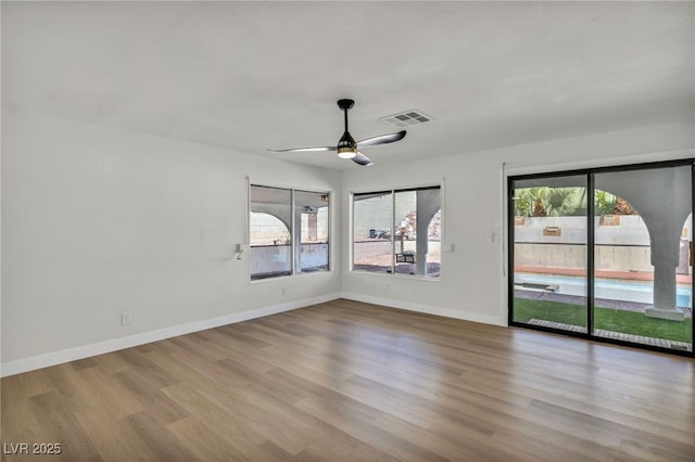 spare room featuring baseboards, ceiling fan, wood finished floors, and visible vents