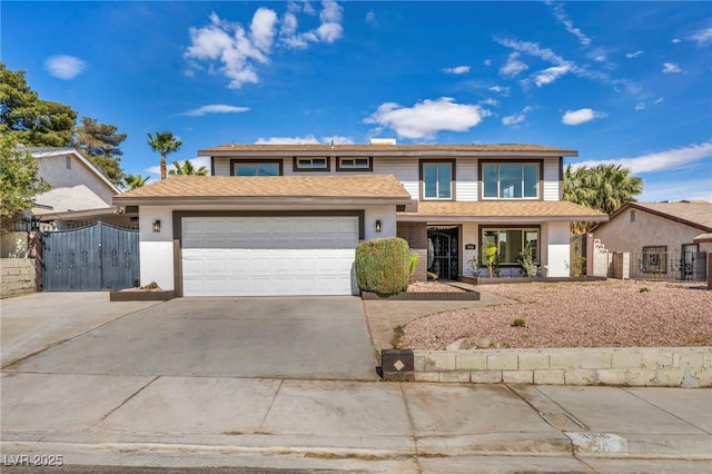 traditional-style home with a garage, a gate, concrete driveway, and fence