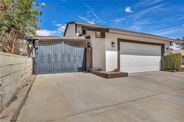 view of front facade featuring a garage, fence, stucco siding, a gate, and driveway