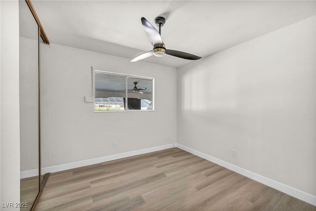 empty room with baseboards, ceiling fan, and wood finished floors