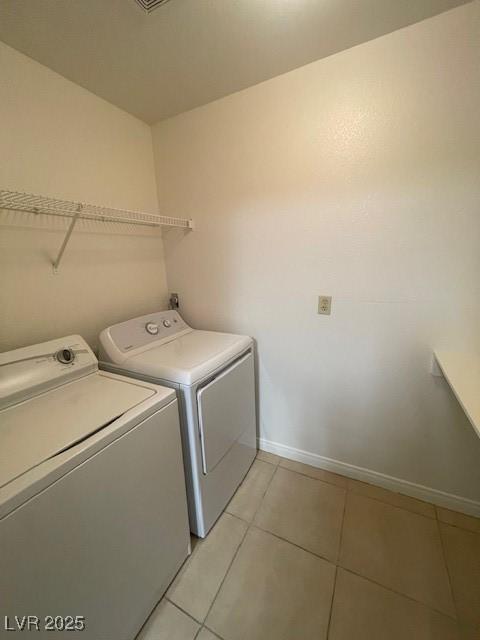 laundry area featuring light tile patterned floors, separate washer and dryer, baseboards, and laundry area