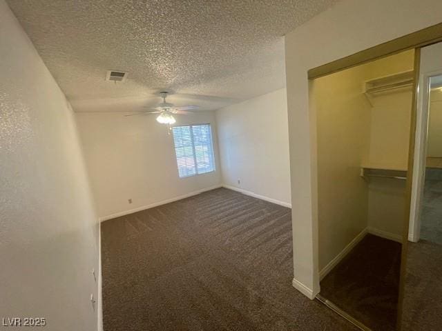 interior space with dark carpet, a textured ceiling, baseboards, and a closet