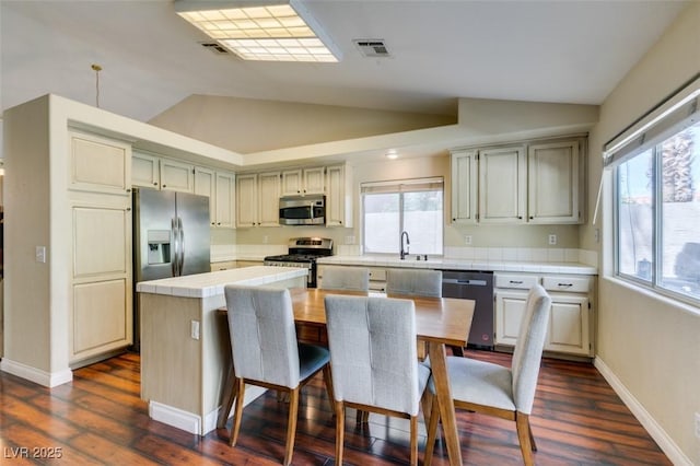 kitchen featuring vaulted ceiling, stainless steel appliances, tile countertops, and visible vents