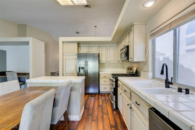 kitchen with tile counters, a sink, dark wood-style floors, and stainless steel appliances