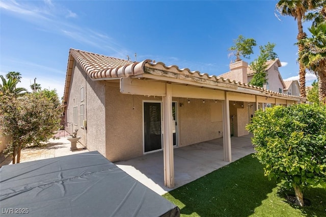 back of property with a patio, a chimney, stucco siding, and a tile roof