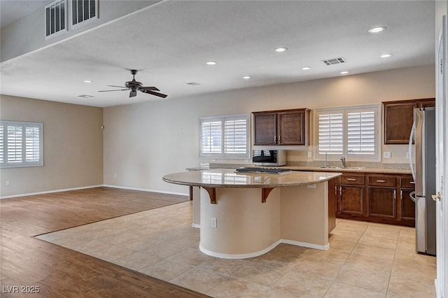 kitchen with a healthy amount of sunlight, light stone countertops, stainless steel appliances, and visible vents