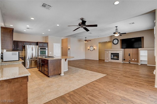 kitchen with light wood-style floors, appliances with stainless steel finishes, ceiling fan, and visible vents