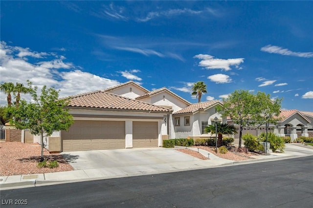 mediterranean / spanish home with an attached garage, concrete driveway, a tile roof, and stucco siding