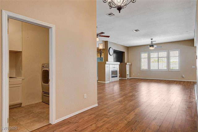 unfurnished living room featuring ceiling fan, visible vents, and a fireplace