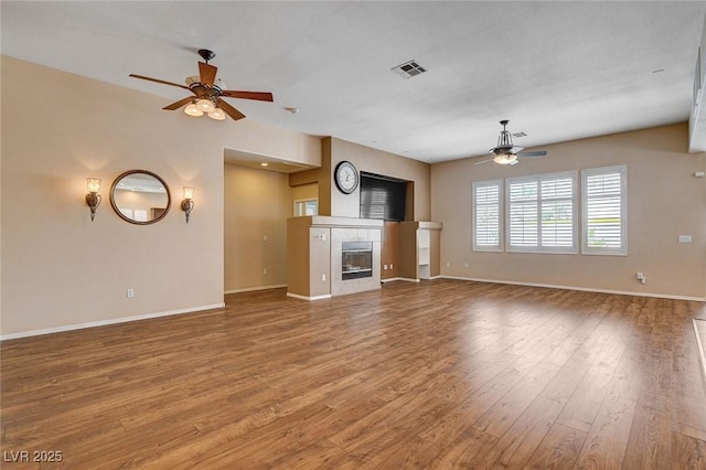 unfurnished living room featuring baseboards, a fireplace, a ceiling fan, and light wood finished floors