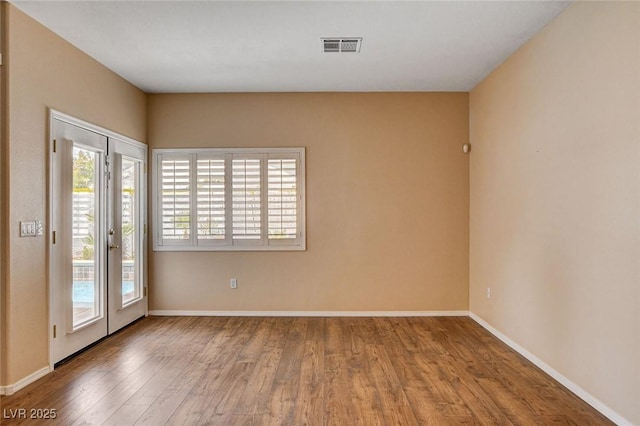 spare room with baseboards, wood finished floors, and visible vents