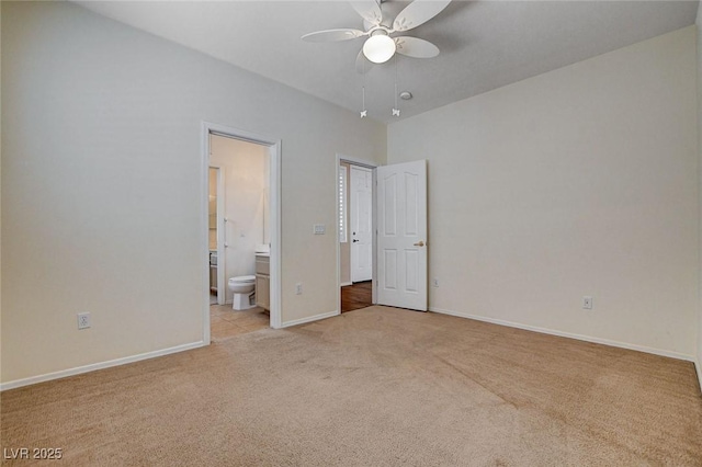 unfurnished bedroom with baseboards, ensuite bathroom, light carpet, and ceiling fan